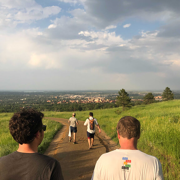People enjoying a hike through a lush, green field on a sunny day