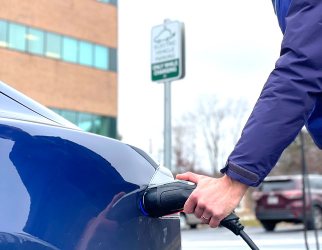 An electric car owner plugs their car into an EV charging station