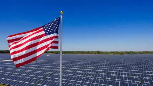 American flag flying above a field of solar panels