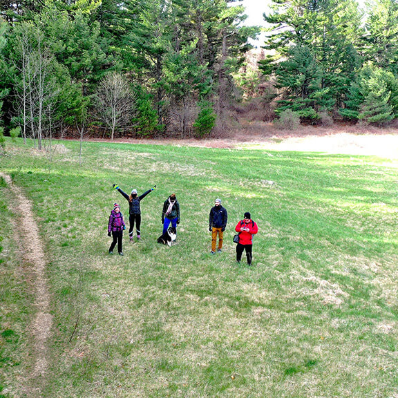 People dressed in outerwear standing in a mountain field